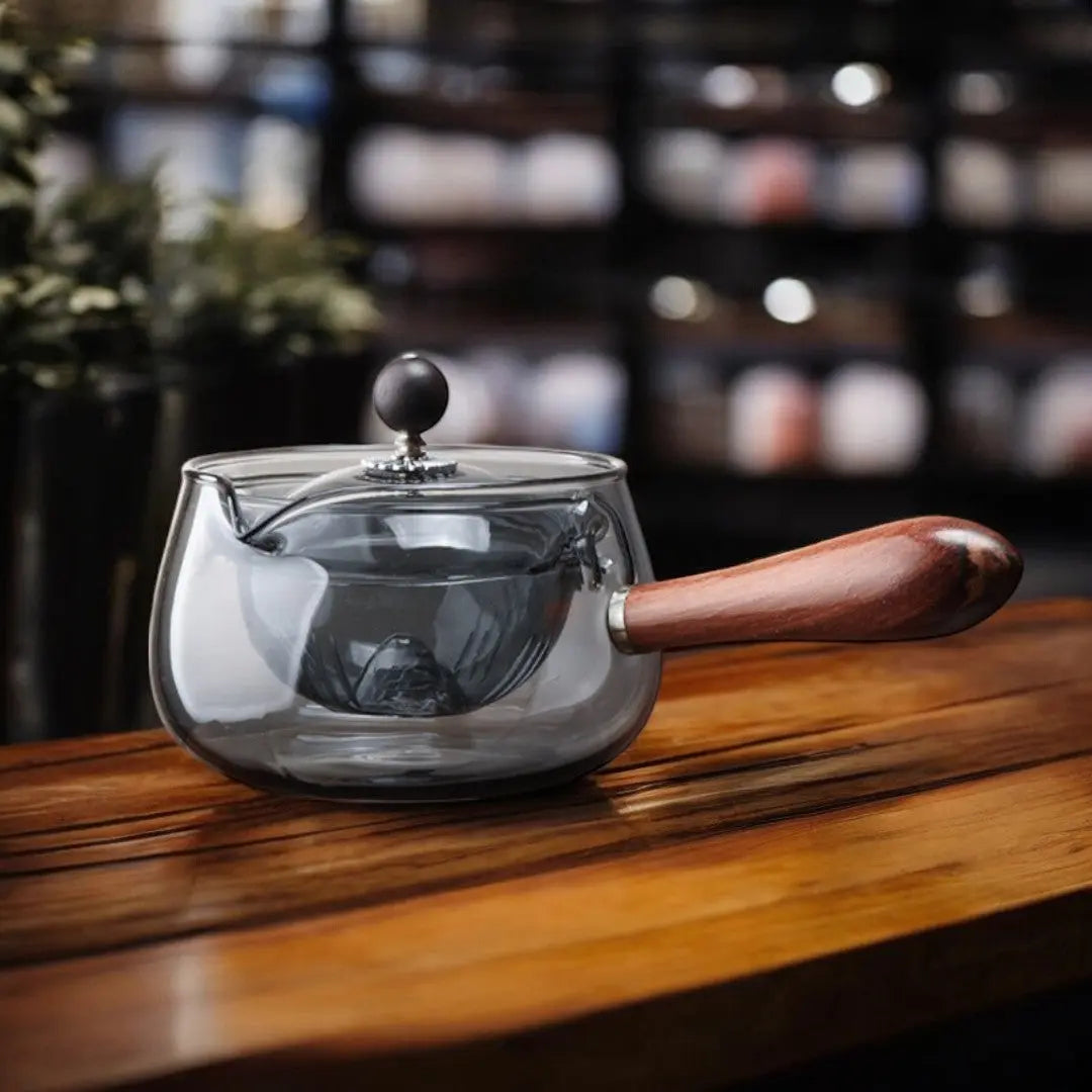 Side profile of smoked gray double-walled glass teapot with wooden handle