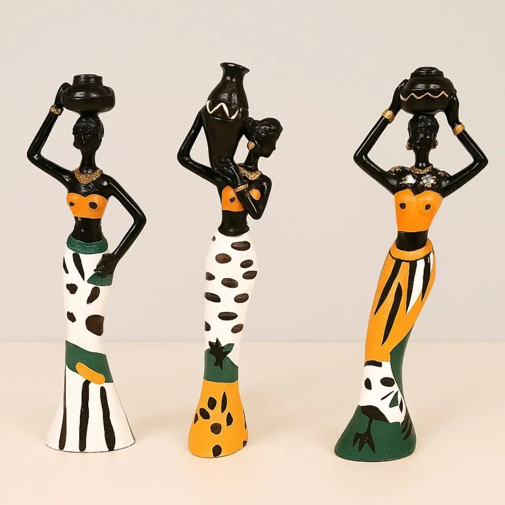 Three-piece African resin figurines of women carrying vessels with orange tops and striped skirts