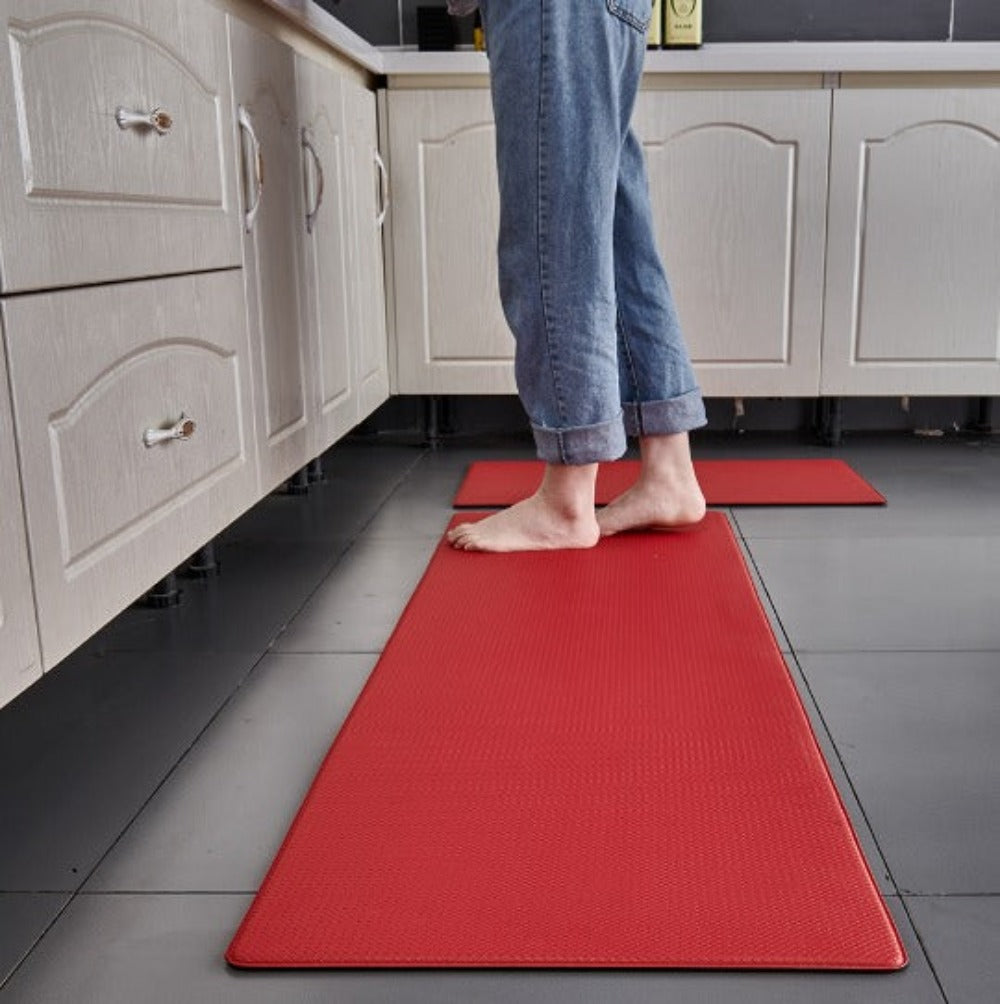 Red anti fatigue kitchen mat with raised dot texture on tiled floor