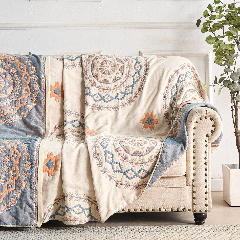 Blue and orange mandala throw blanket draped over beige sofa