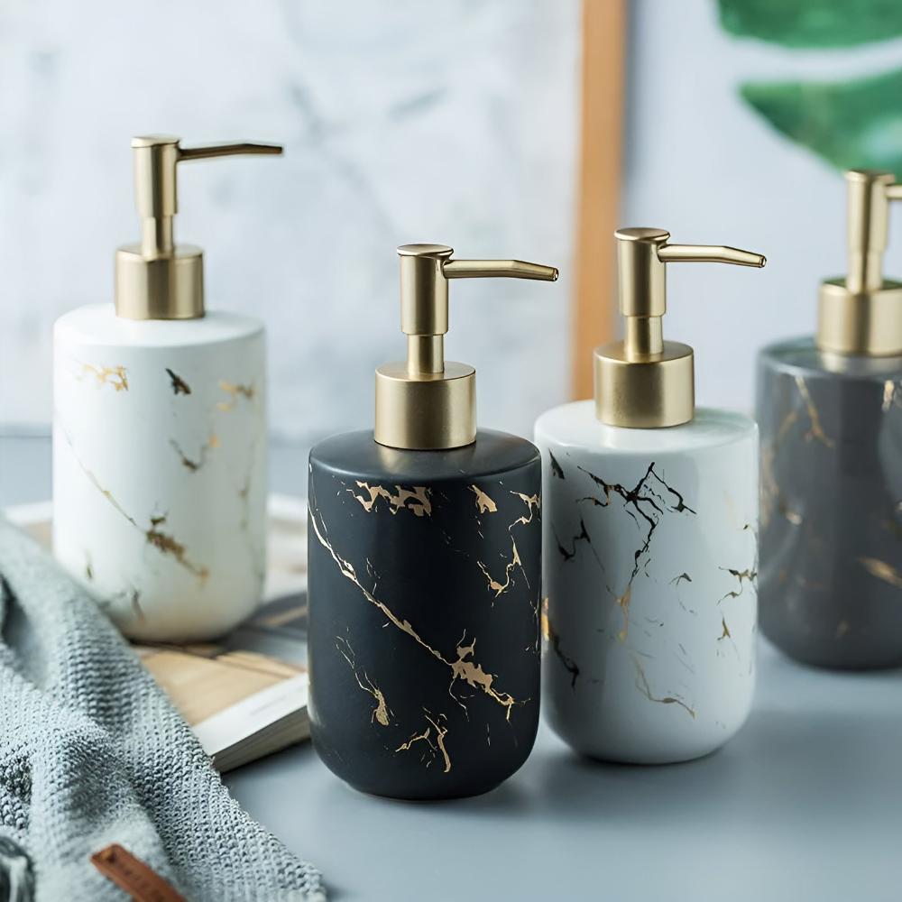 Set of four ceramic soap dispensers in black, white, and gray with gold pumps