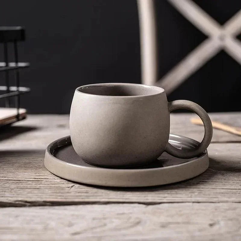 Two-tone gray speckled ceramic coffee cup and saucer with dark glaze interior