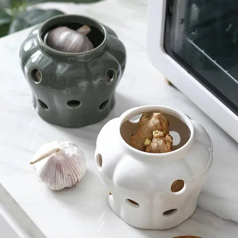Two ceramic garlic keeper jars in gray-green and white with bamboo lids on marble