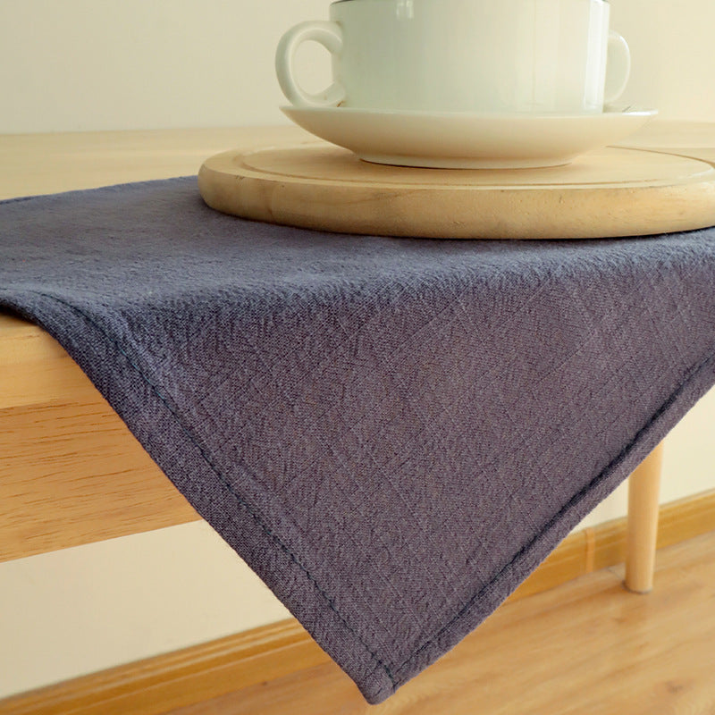 Dark blue-gray linen napkin draped over table corner with tea set