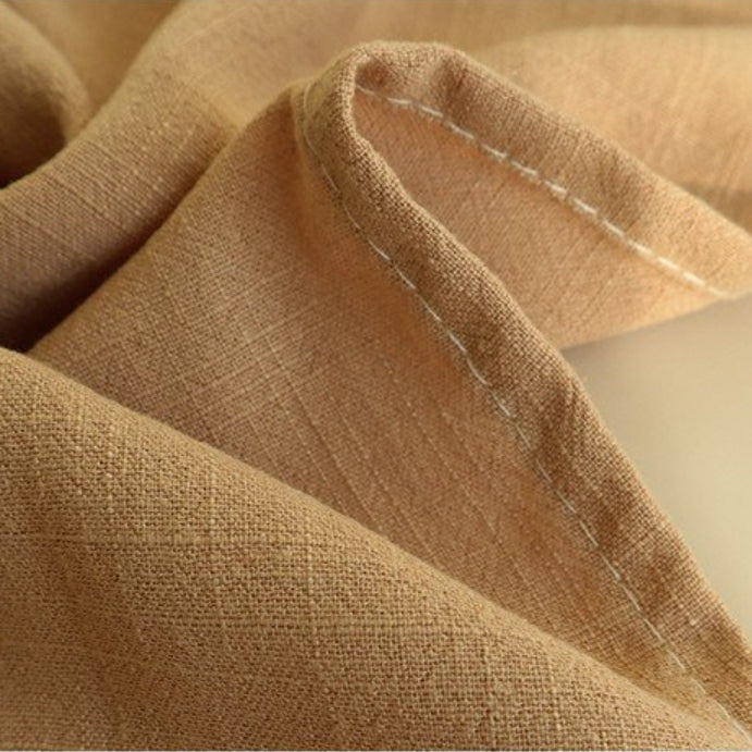 Beige linen napkin detail shot highlighting woven texture and white stitching