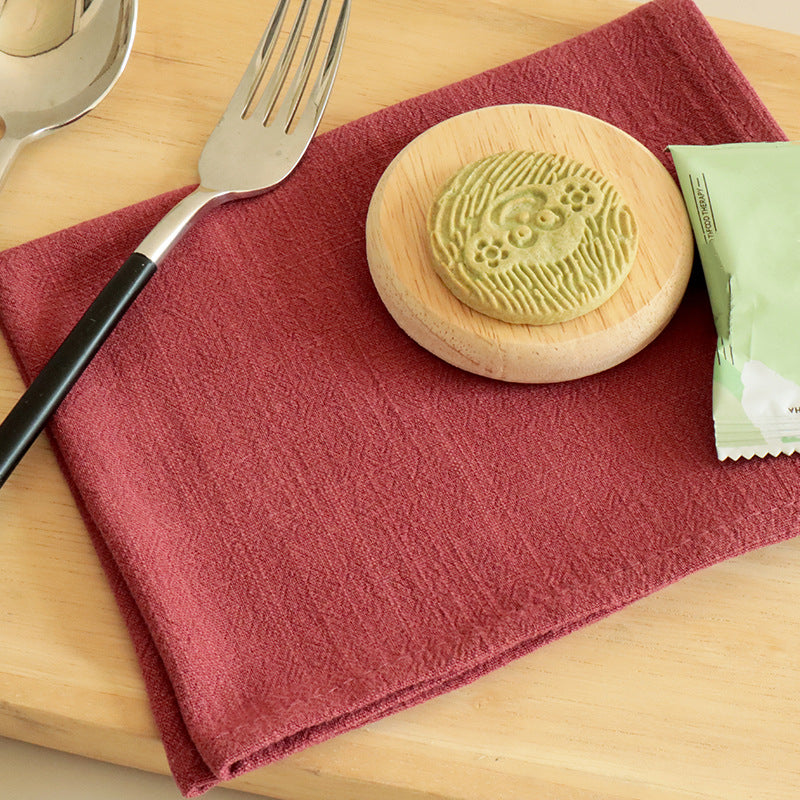 Deep red cotton linen napkin folded neatly with matcha cookie and silverware