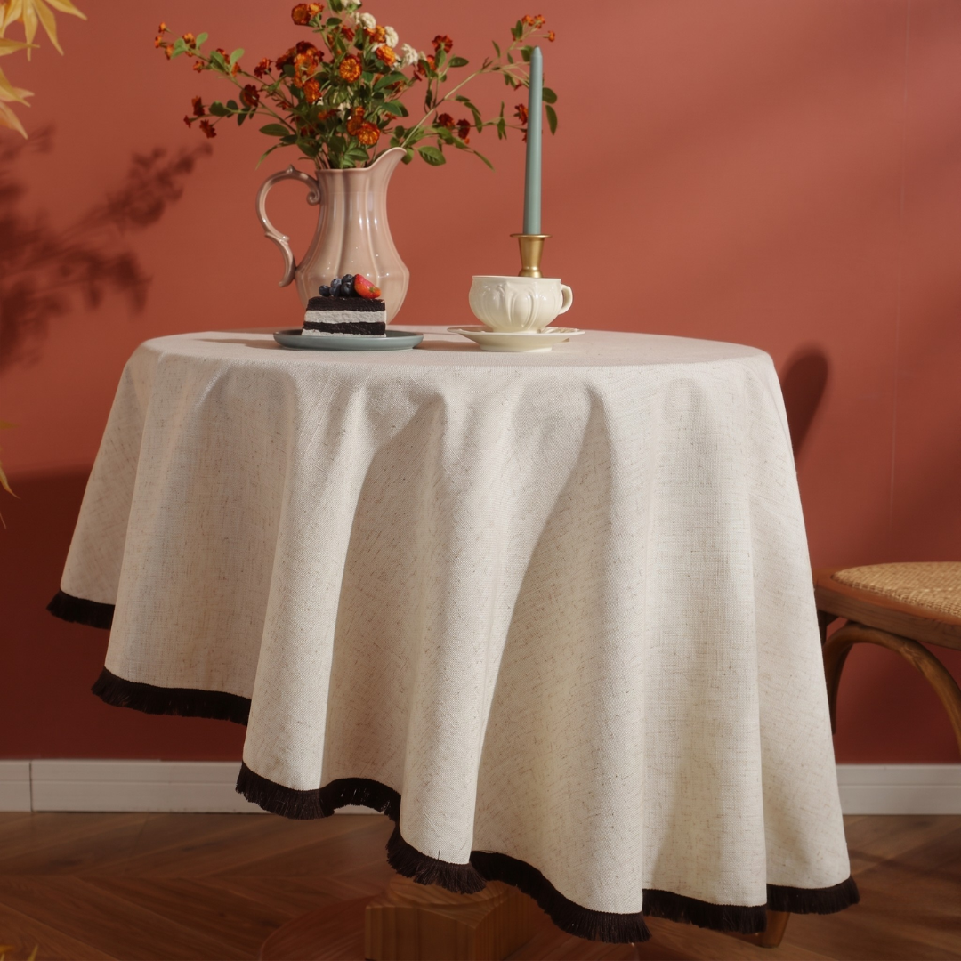 Cream textured tablecloth draped on round table with flowers