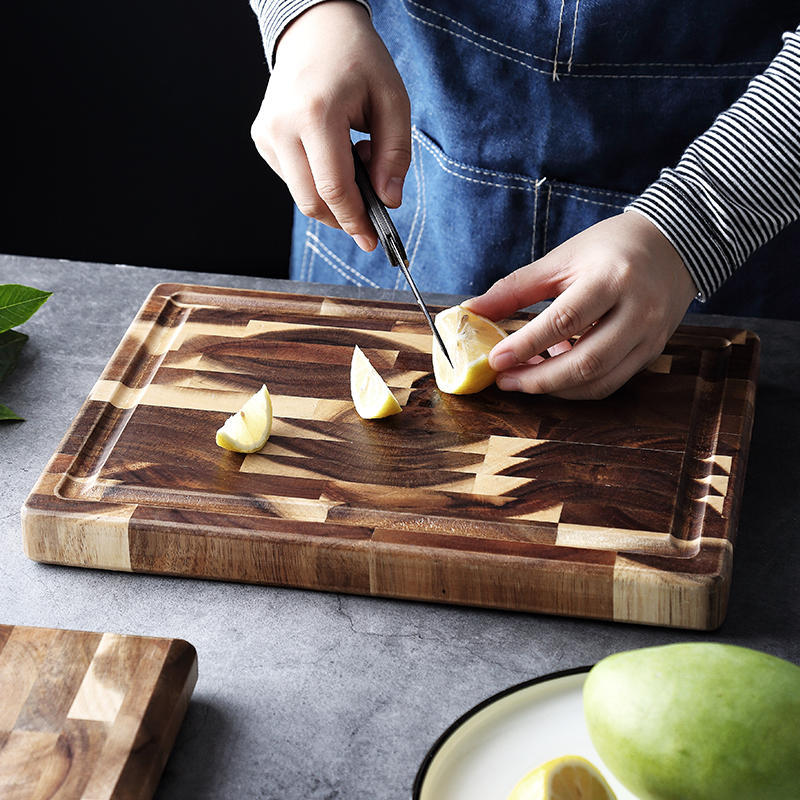 Person slicing lemon on thick end grain wooden cutting board with juice groove