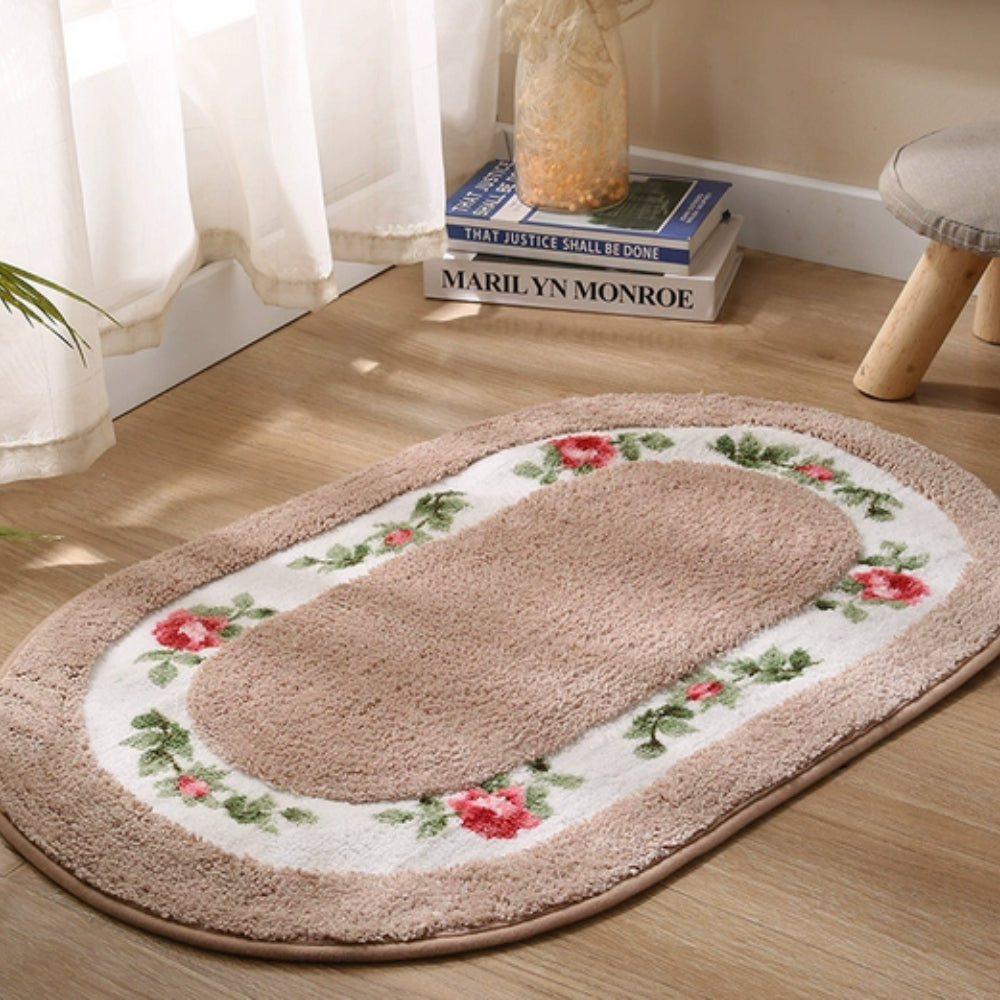 Beige oval bath mat with red rose floral border near window and sheer curtains