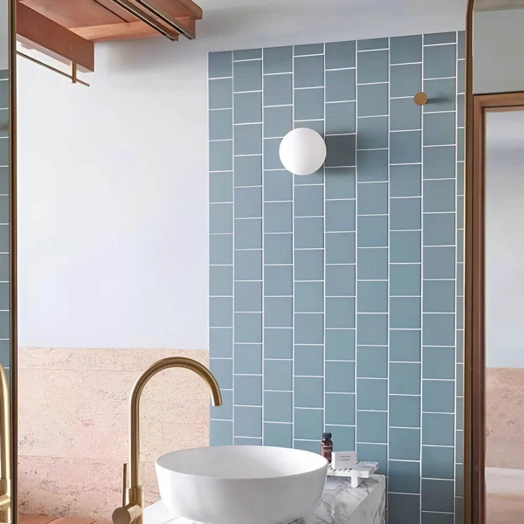 Spherical frosted glass bathroom sconce above vessel sink on tiled wall