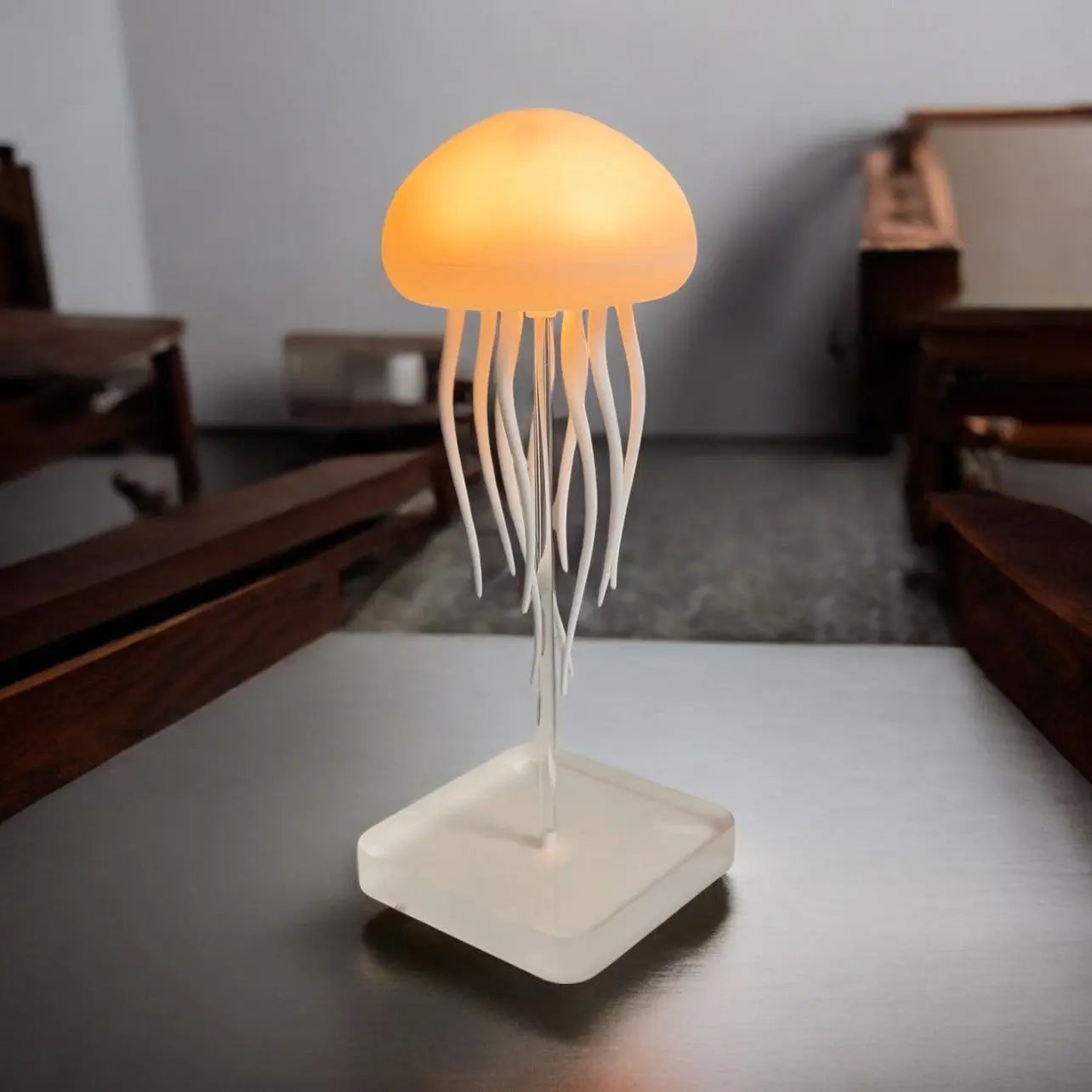 Warm yellow-orange jellyfish table lamp with translucent dome and acrylic square base