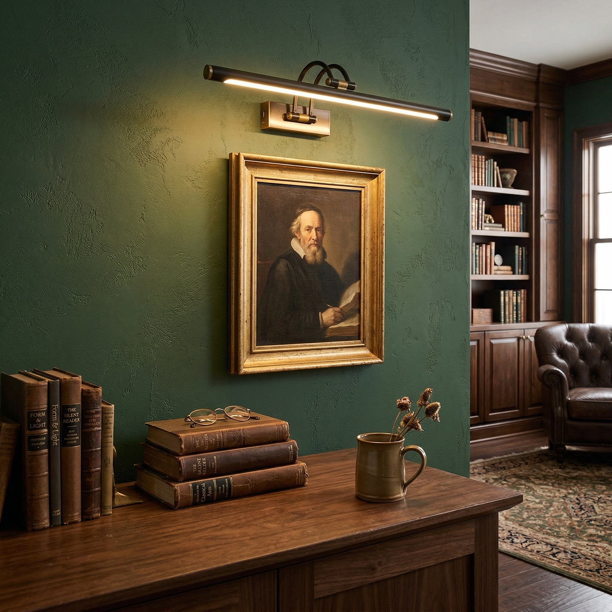 Brass wall sconce illuminating framed portrait on dark green gallery wall