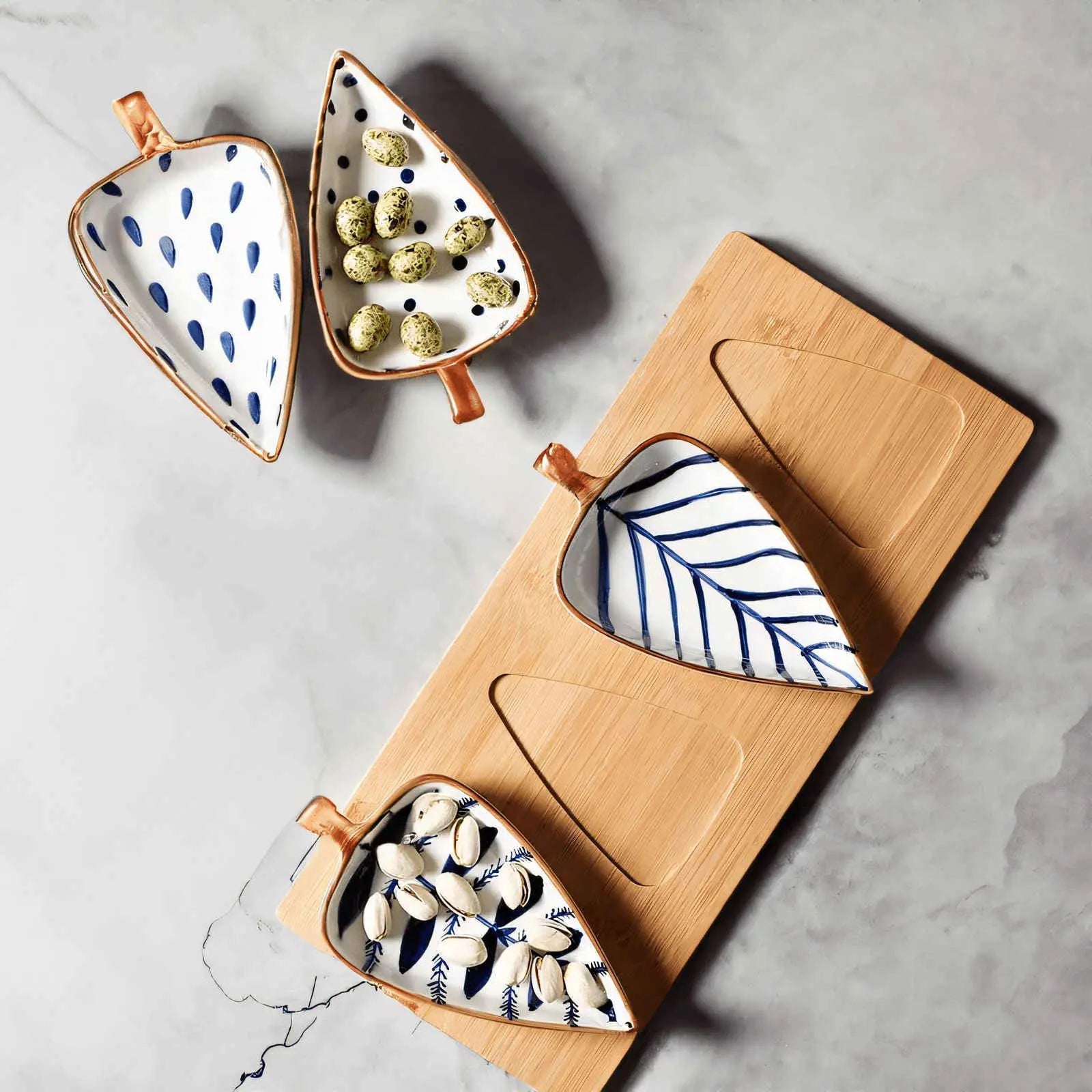 Bamboo tray set with two ceramic leaf plates filled with pistachios and quail eggs