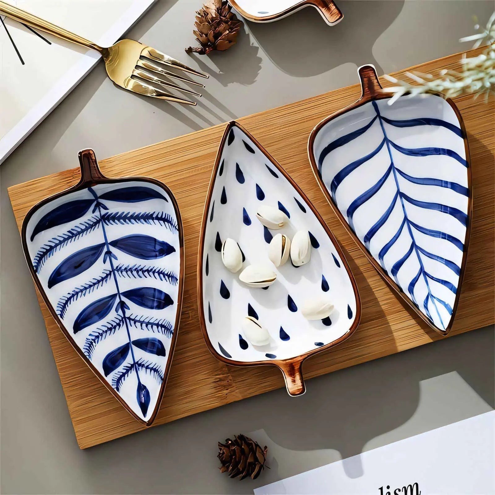 Three botanical pattern ceramic leaf serving dishes on bamboo tray with gold rim
