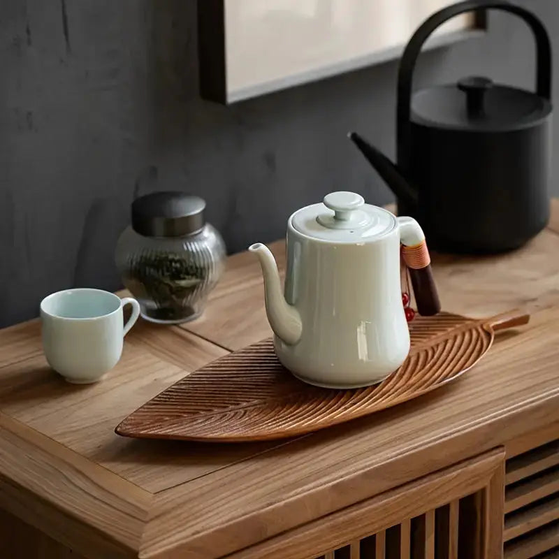 Carved wood leaf serving platter displaying kettle and tea accessories