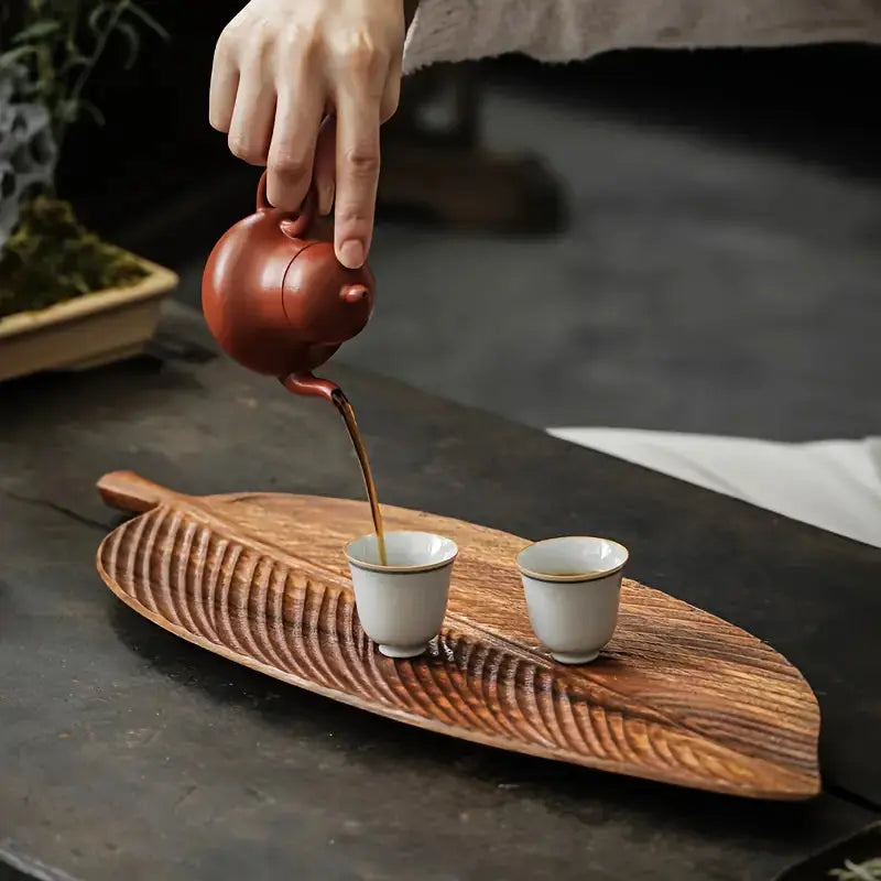 Leaf shaped wooden serving tray with carved vein texture holding tea set