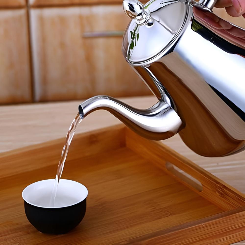 Pouring water from stainless steel tea kettle with narrow spout into ceramic cup