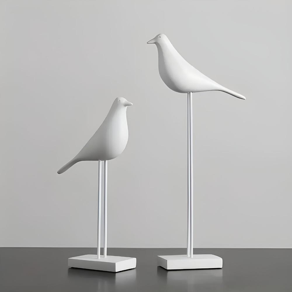 Matte white minimalist bird statues side by side on dark reflective surface