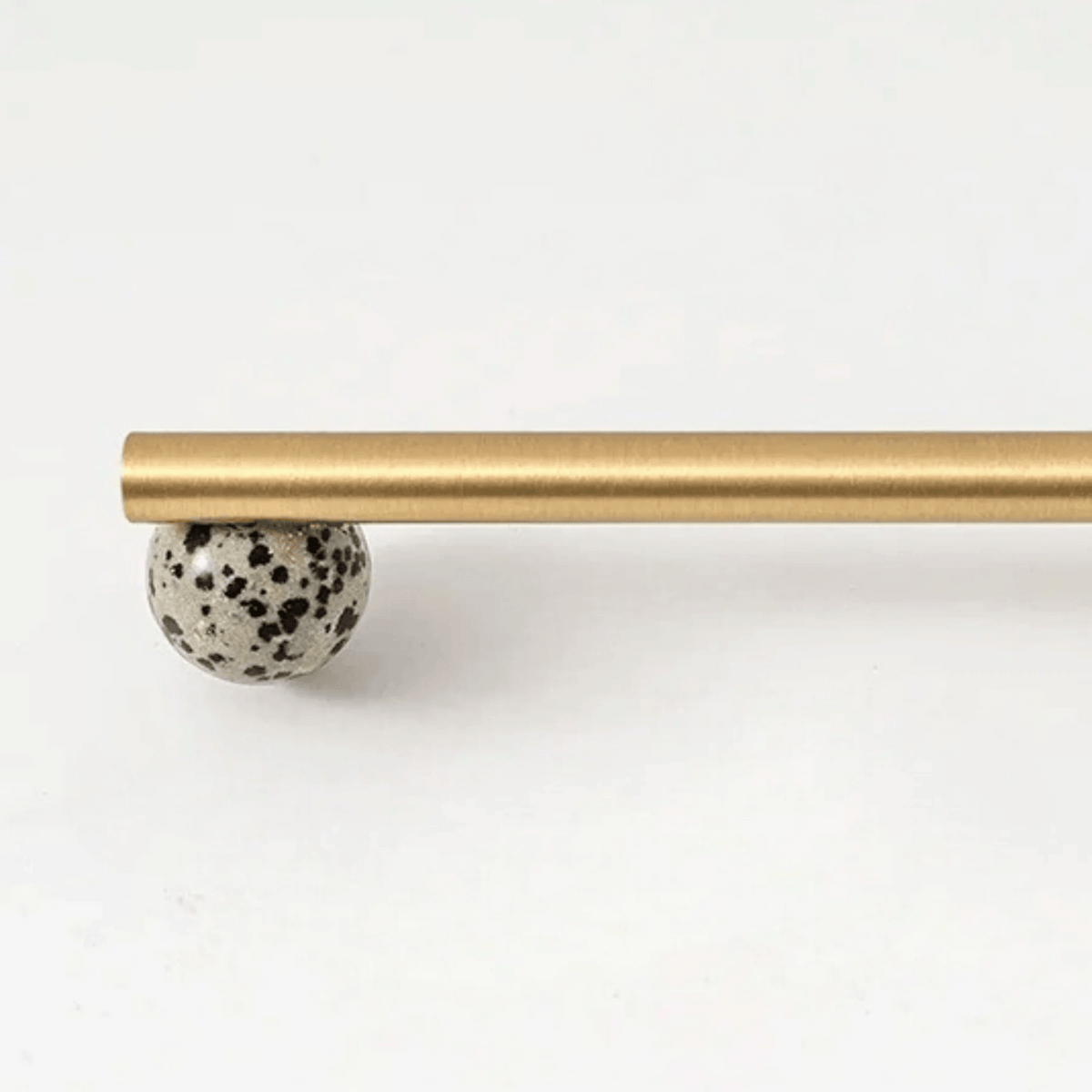 Matte gold brass handle with black speckled stone sphere detail