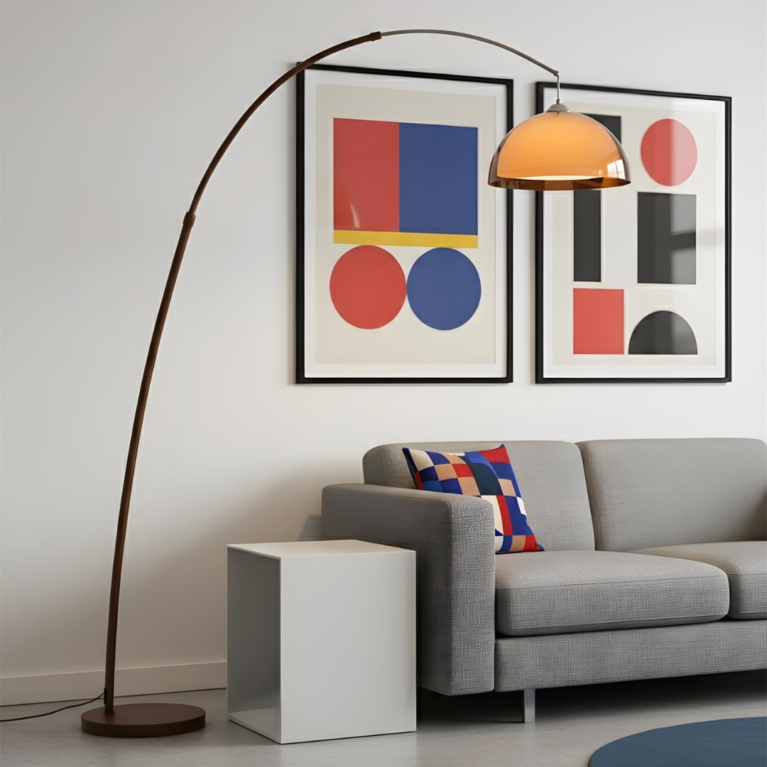 Modern arc floor lamp with walnut finish and amber dome shade beside gray sofa