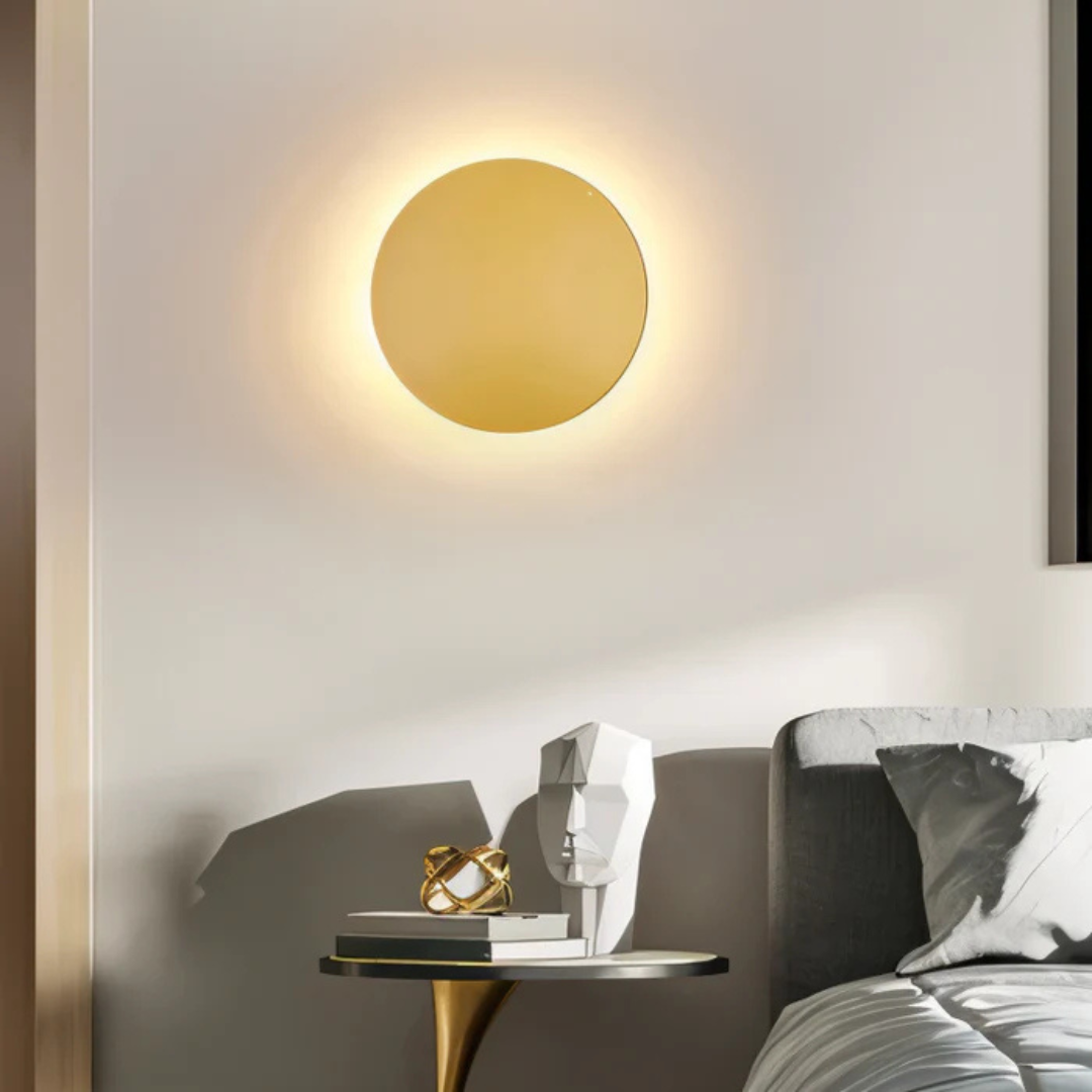 Gold matte disc LED wall fixture above side table with decor