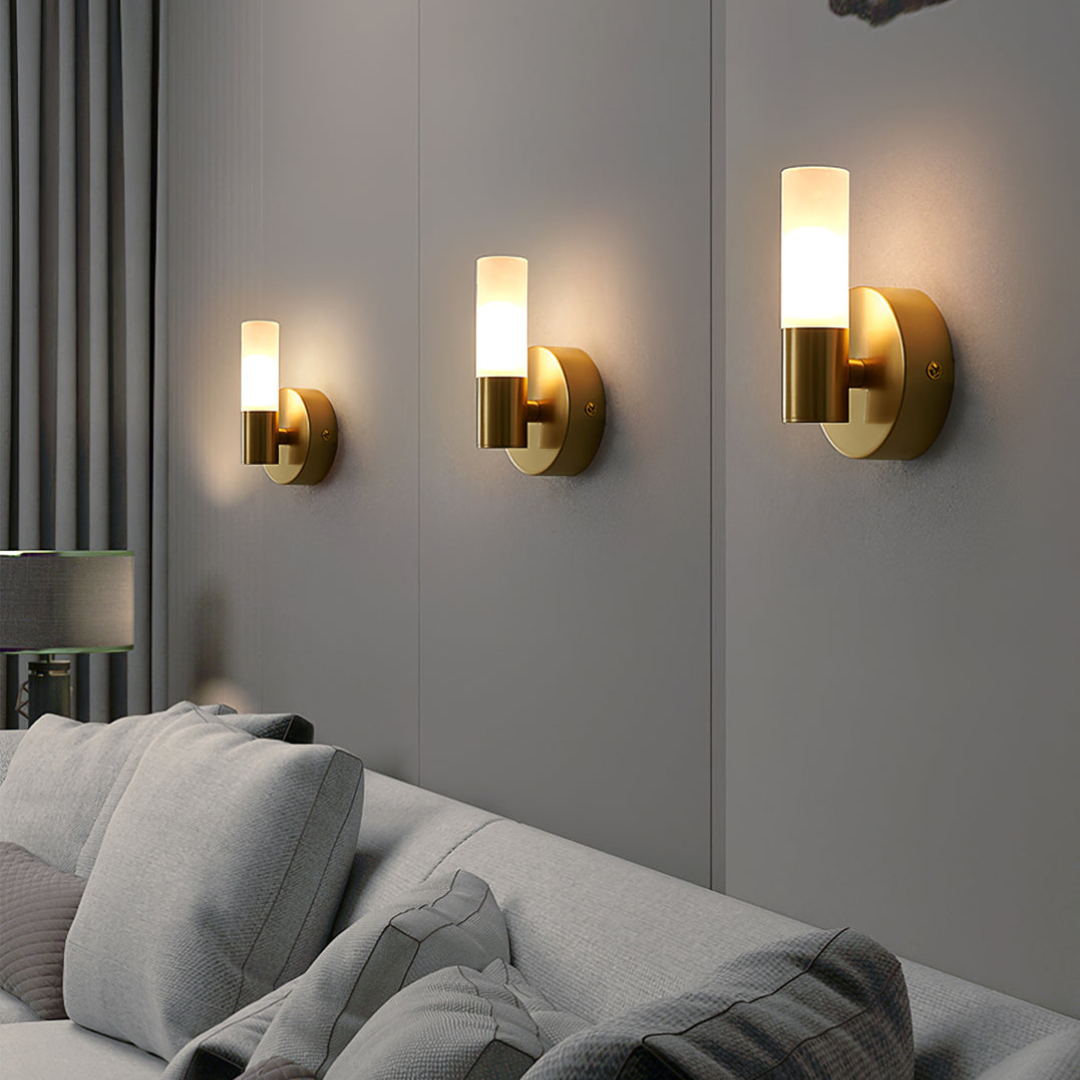 Modern brass dual-light wall sconce with frosted glass cylinders in hallway setting