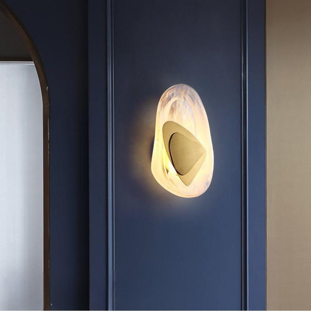 Brushed gold layered triangle wall lamp mounted on navy blue paneled wall