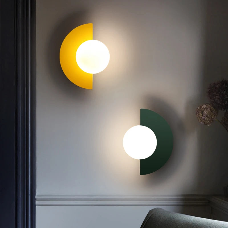 Asymmetric yellow and dark green LED wall lights with round white shades near door frame