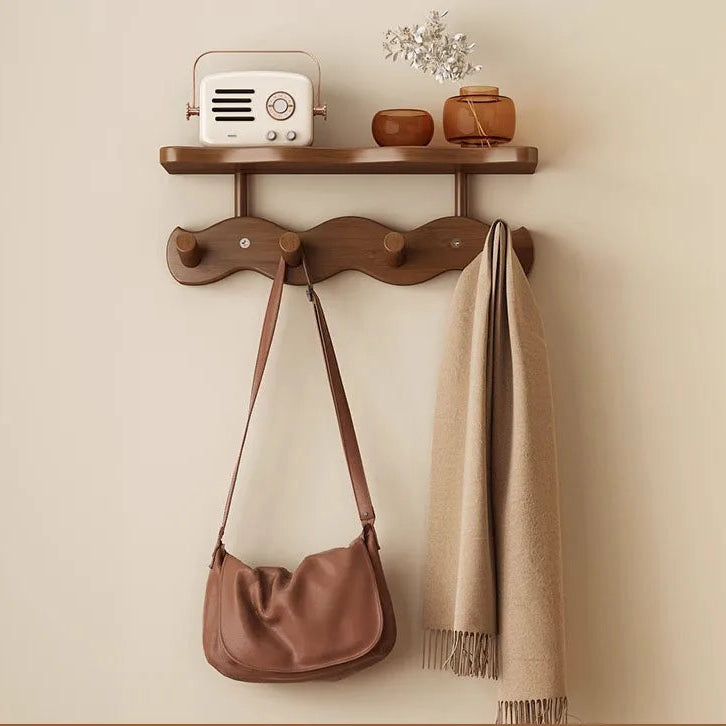 Close-up of dark bamboo shelf and wavy hook bar holding leather bag and scarf