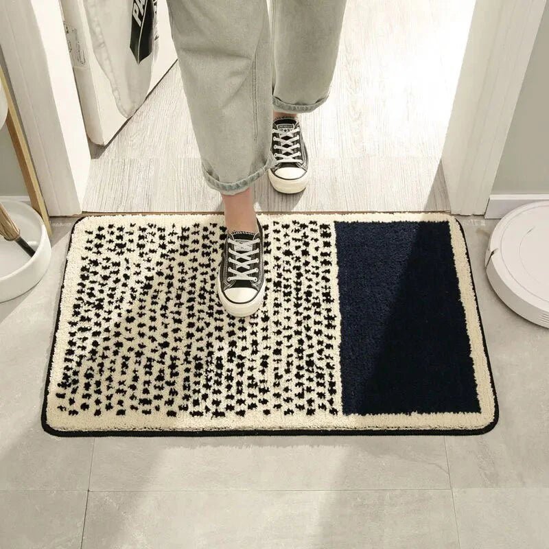 Person standing on navy blue and cream abstract dot plush bath mat