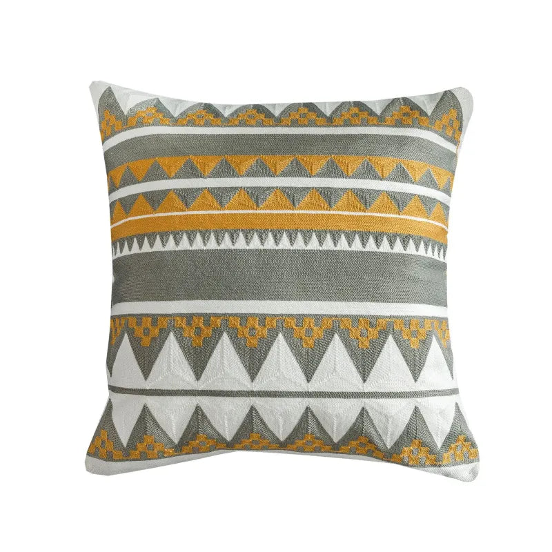 Mustard yellow and gray embroidered pillow featuring triangle and diamond motifs