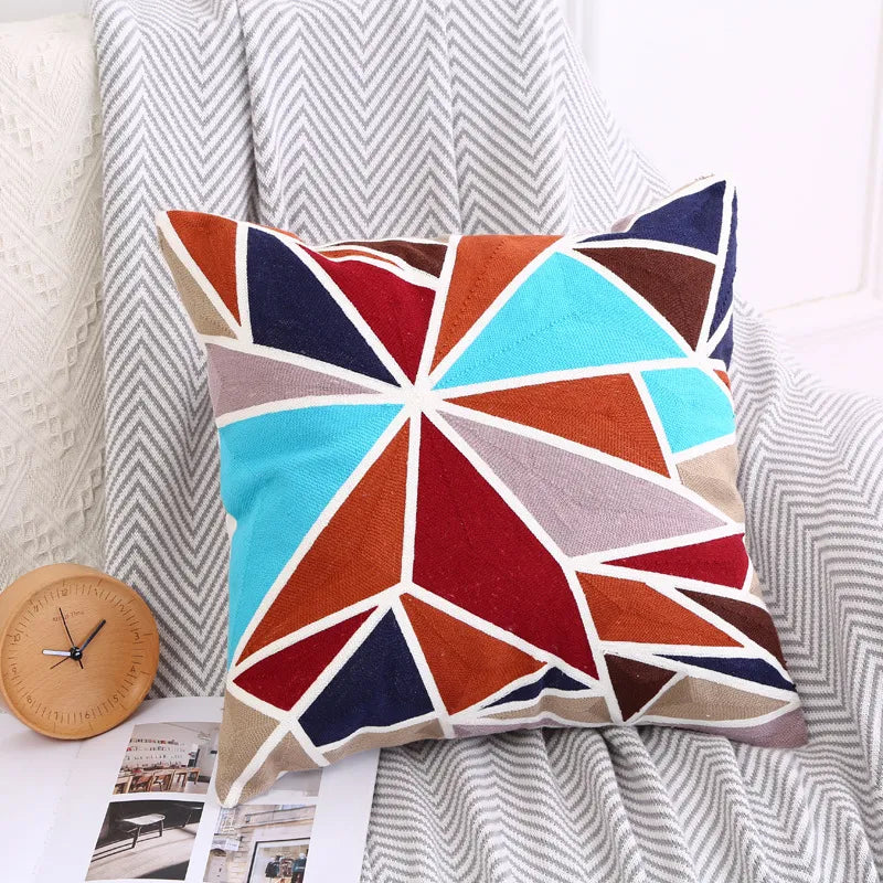 Multi-color radial geometric embroidery throw pillow with teal and red accents