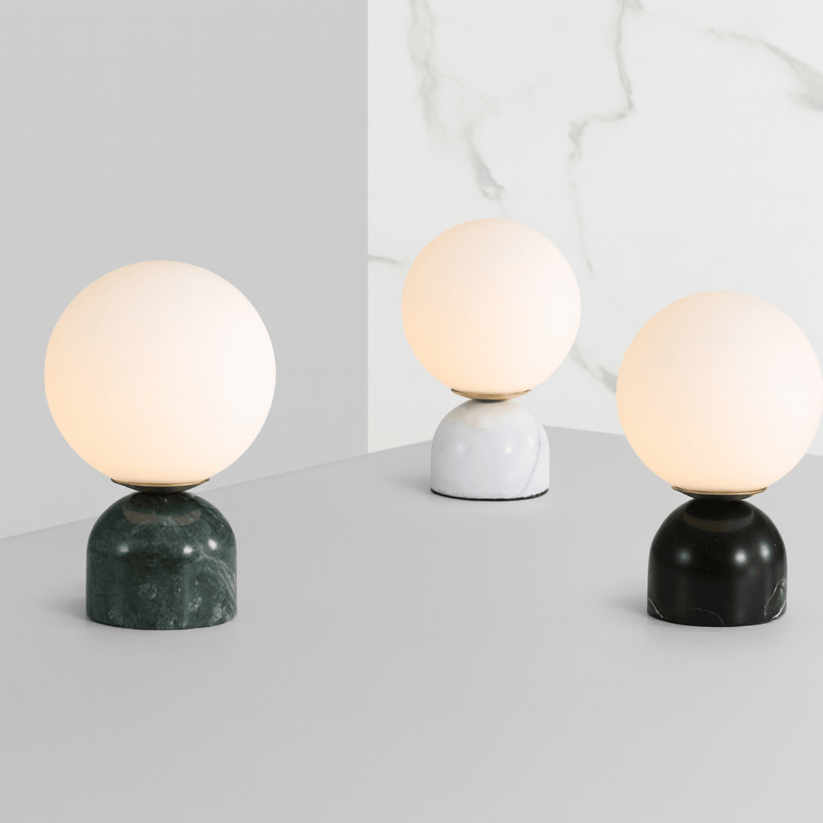 Artistic arrangement of green, white, and black marble table lamps with marble backdrop
