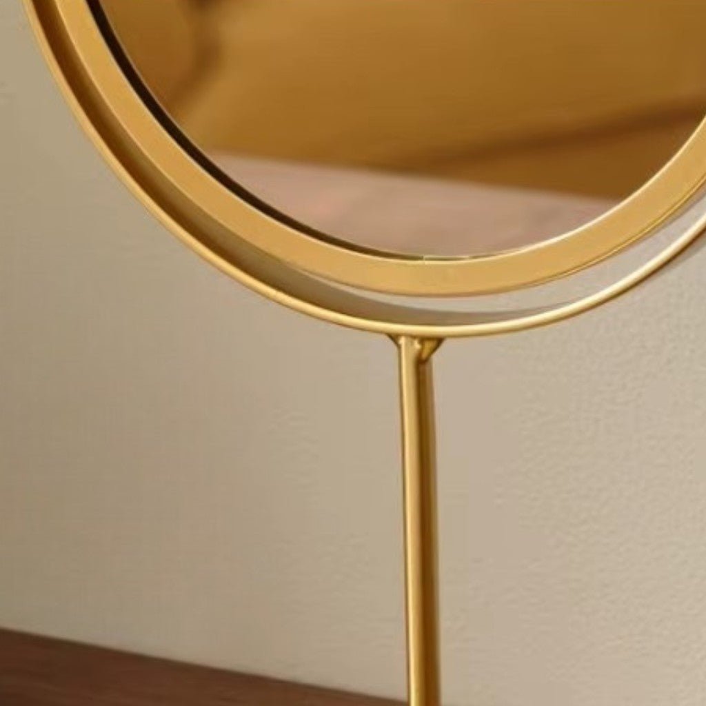 Detail shot of matte gold oval mirror frame connecting to slender stand