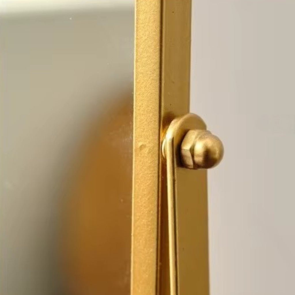 Close-up of matte gold oval mirror hinge mechanism and textured frame