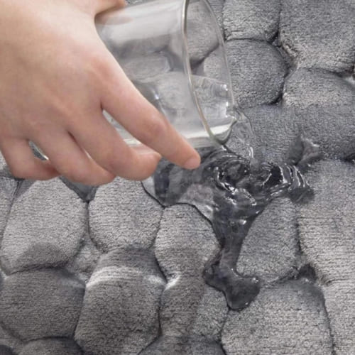 Close-up of gray quick-dry bath mat absorbing water on cobblestone texture