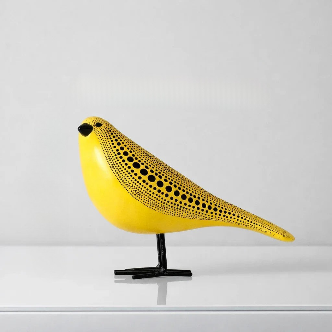 Yellow polka dot bird figurine on black stand with streamlined wing details