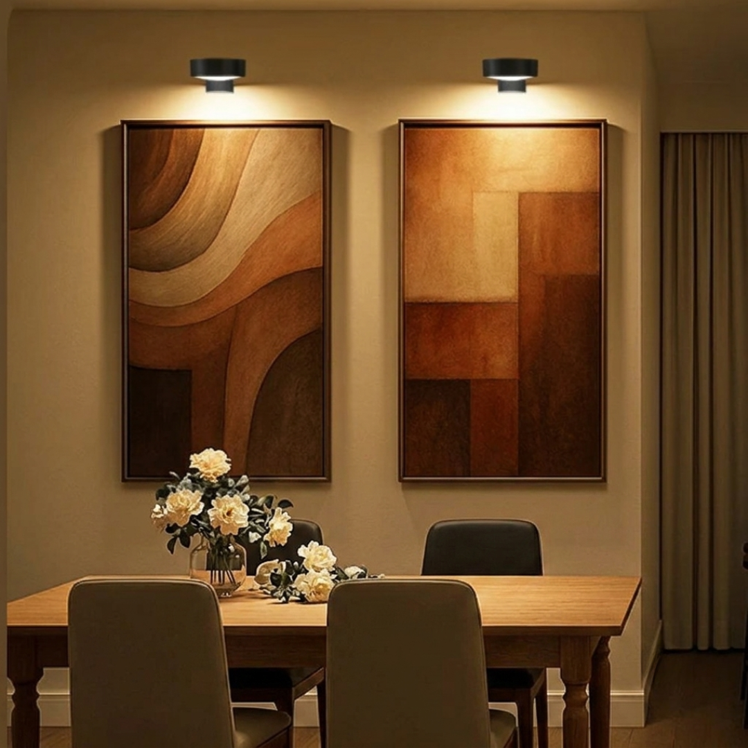 Wireless gold picture lights illuminating framed art in dining room