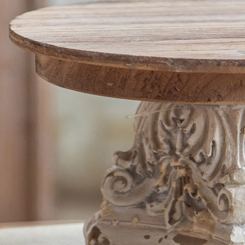 Close-up of hand-carved scrollwork on distressed antique-style wooden stand