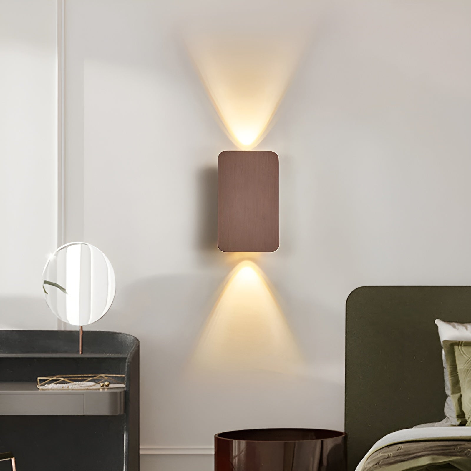 Brushed bronze wall lamp between vanity and bed casting soft dual conical light