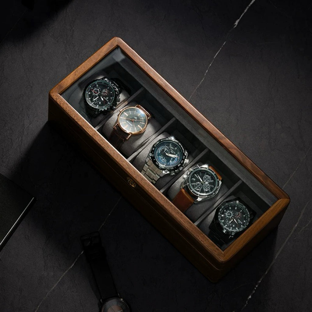 Dark wood watch storage box with glass top holding five chronograph watches
