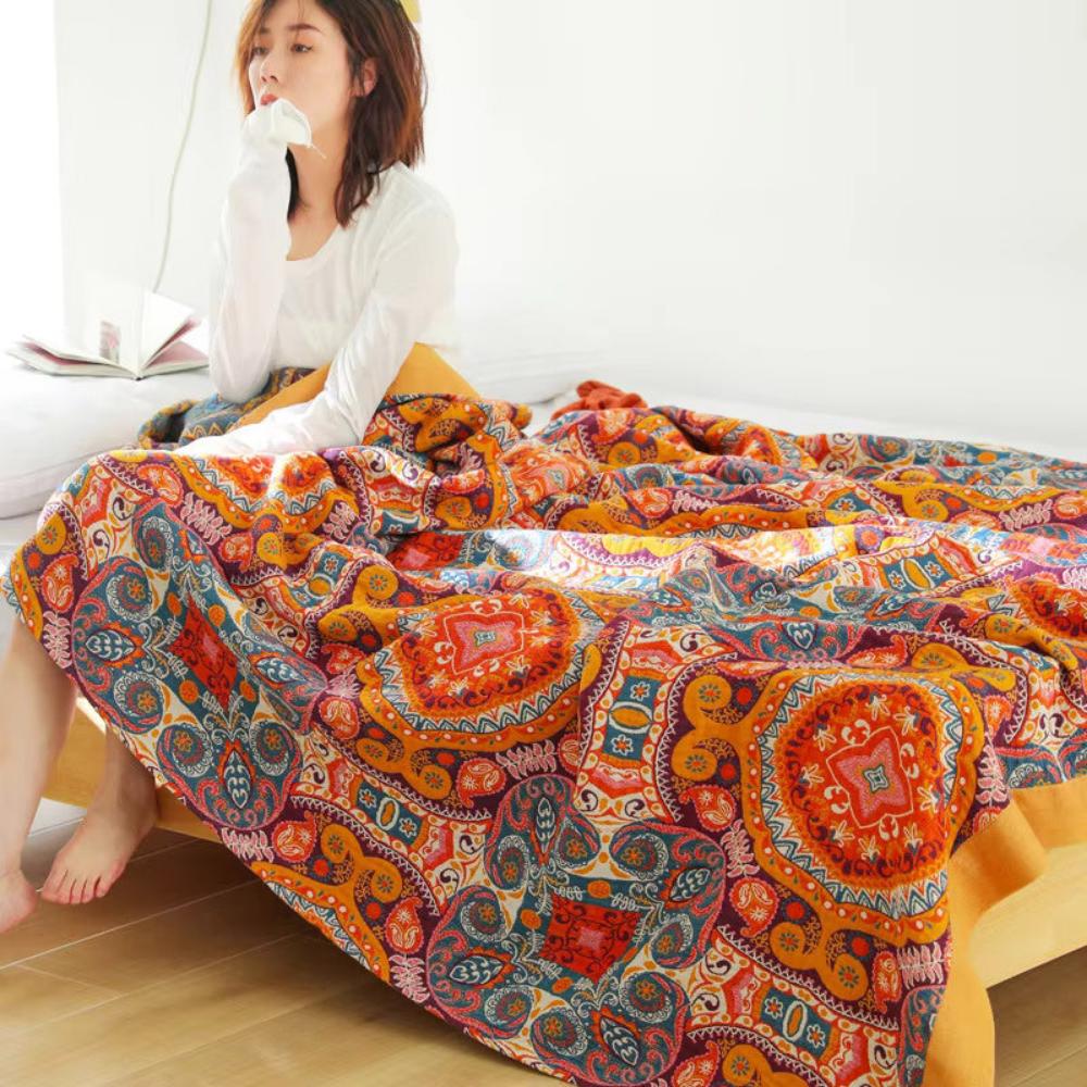 Woman relaxing on bed covered by soft reversible boho blanket with dense mandala print