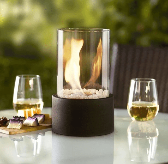 Black concrete fire pit with wine and cheese on white table