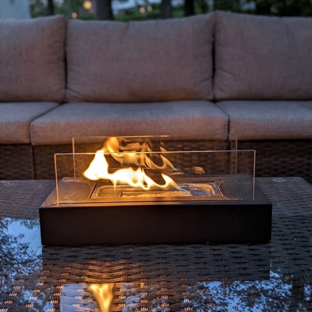 Reflective flame view of matte black fire pit on dark wicker coffee table