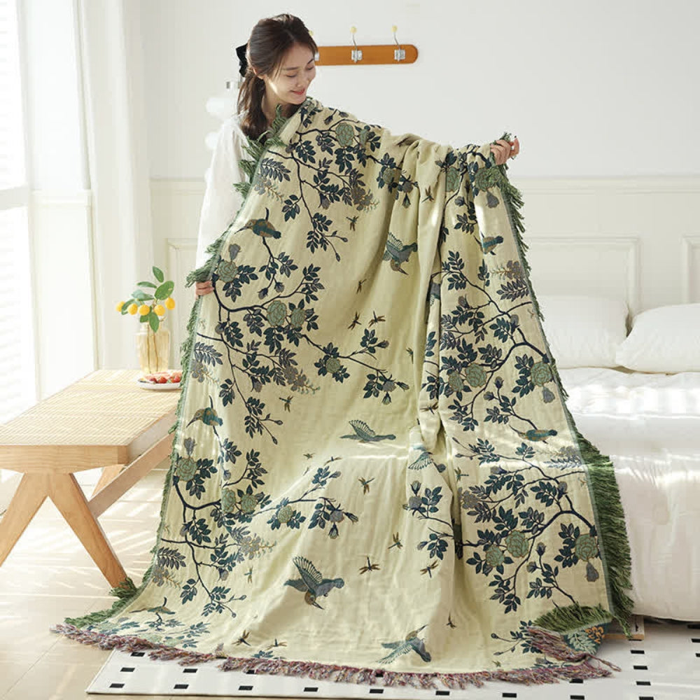 Beige vintage botanical throw blanket with jacquard leaves and birds held open