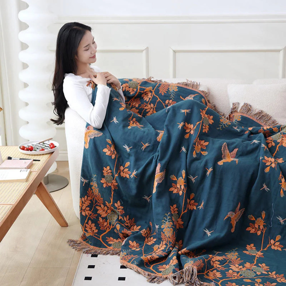 Teal vintage botanical throw blanket with fringe detail over sofa armrest