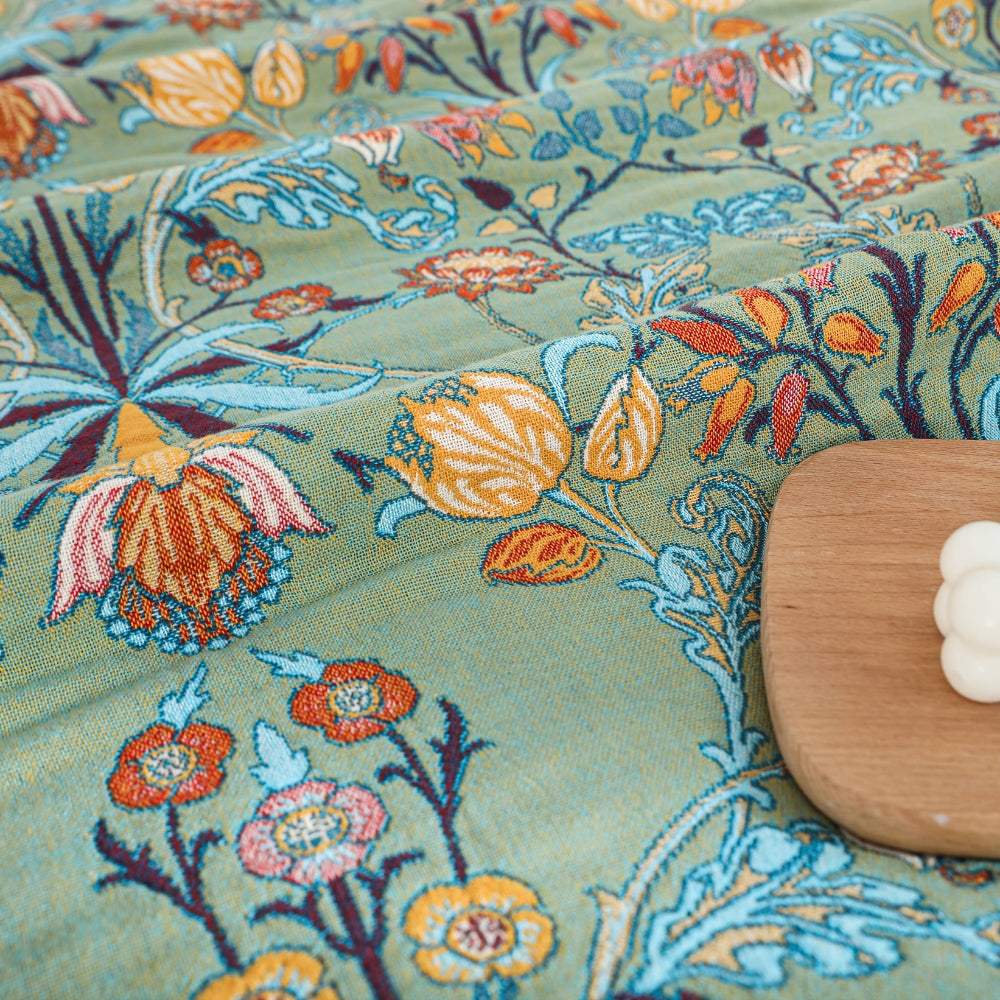 Textured green floral cotton throw blanket flat-lay with wooden board