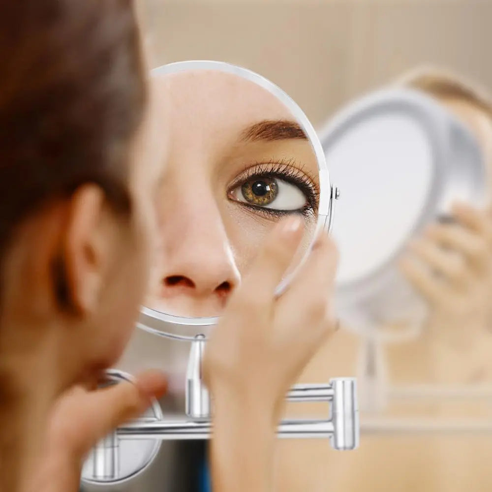 Close up of magnifying side of chrome wall mounted makeup mirror for detailed eye makeup application