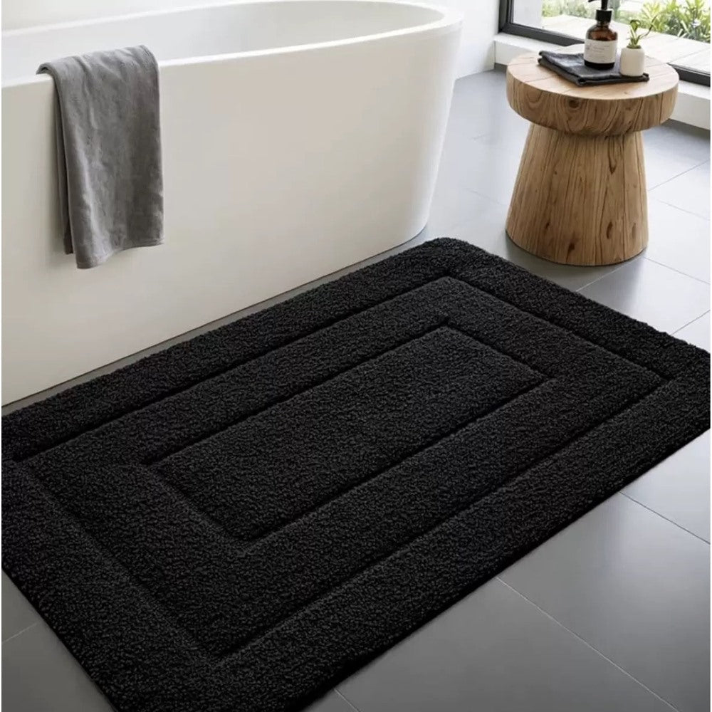 Maintained House Plush Microfiber Bath Mat - Black, beside a bathtub