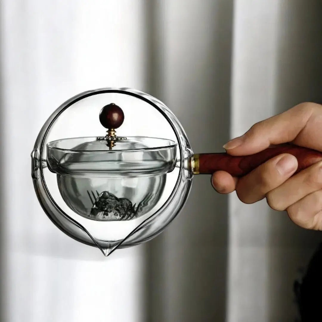 Close-up of rotating mechanism on smoked gray glass teapot with leaves
